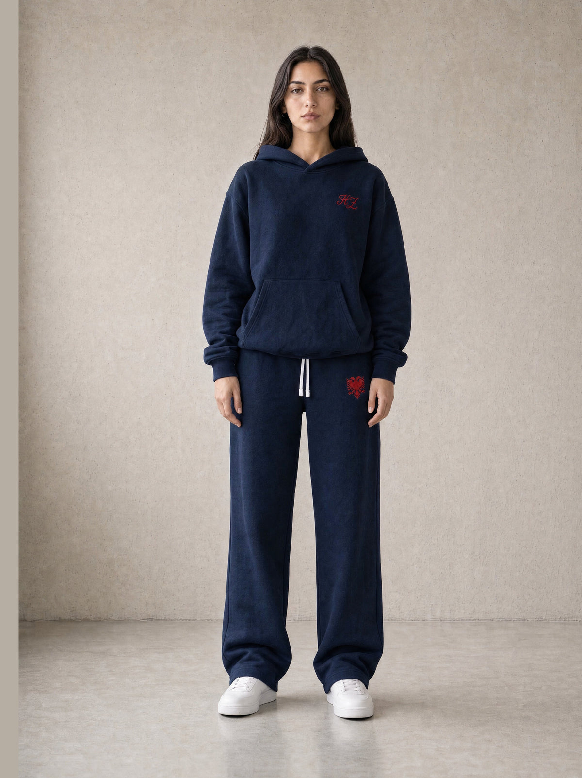 Design preview: Hajde Zemer HZ Essential Eagle Set in blue navy, front view on a female model, red eagle on the sweatpant thigh