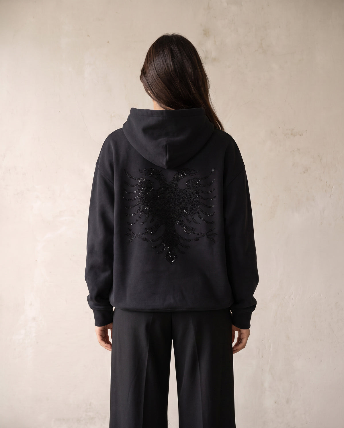 Eagle Rhinestone Hoodie in black, worn back view on a female model - Albanian double headed eagle in tonal black rhinestones