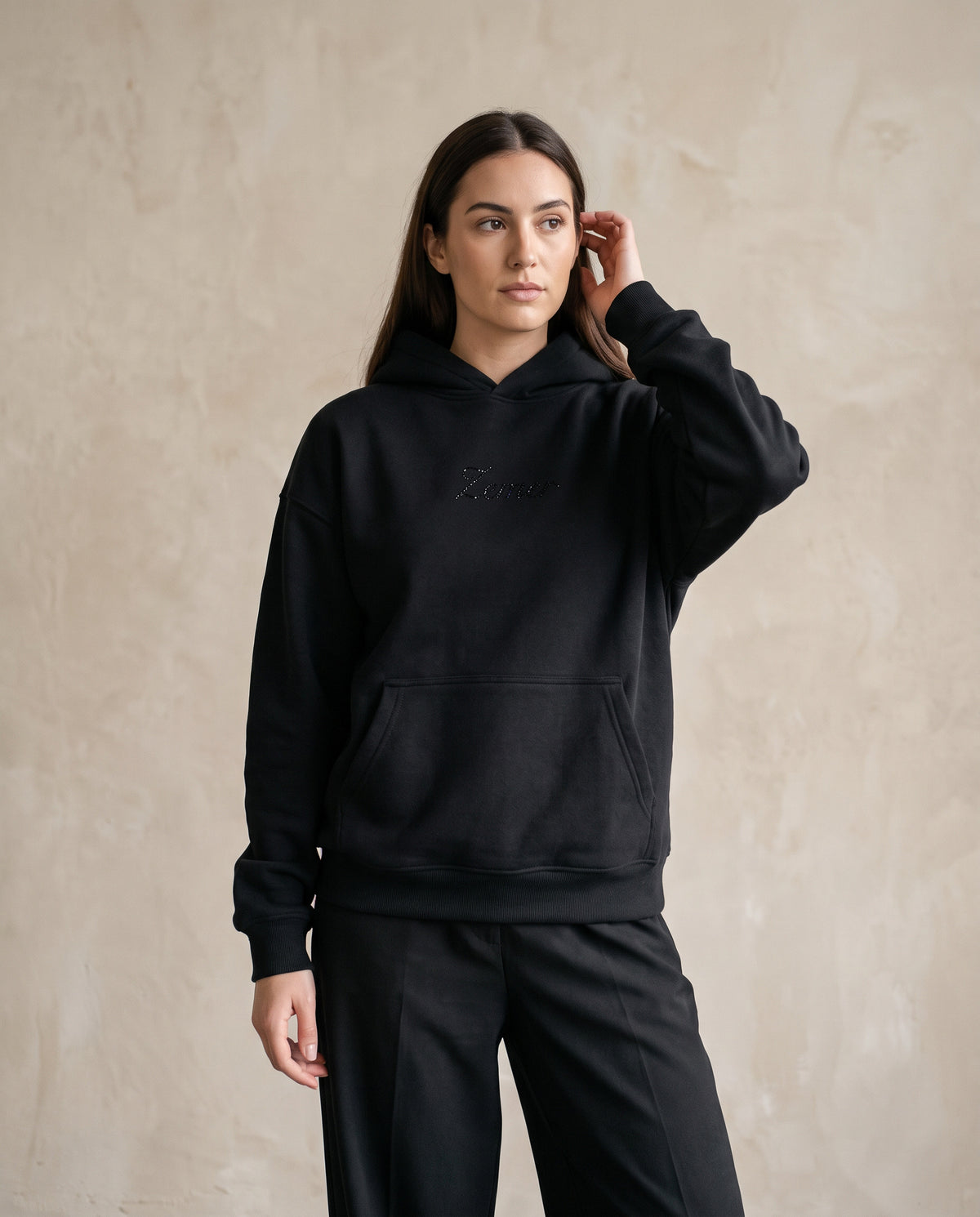 Eagle Rhinestone Hoodie in black, worn front view on a female model - black rhinestone Zemer script at the chest