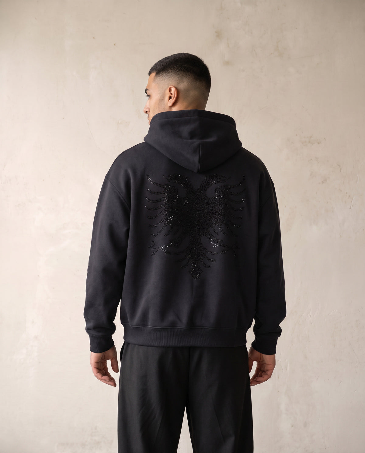 Eagle Rhinestone Hoodie in black, worn back view on a male model - Albanian double headed eagle in tonal black rhinestones