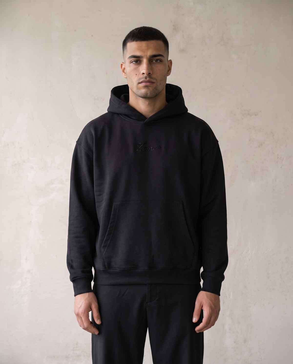 Eagle Rhinestone Hoodie in black, worn front view on a male model - black rhinestone Zemer script at the chest