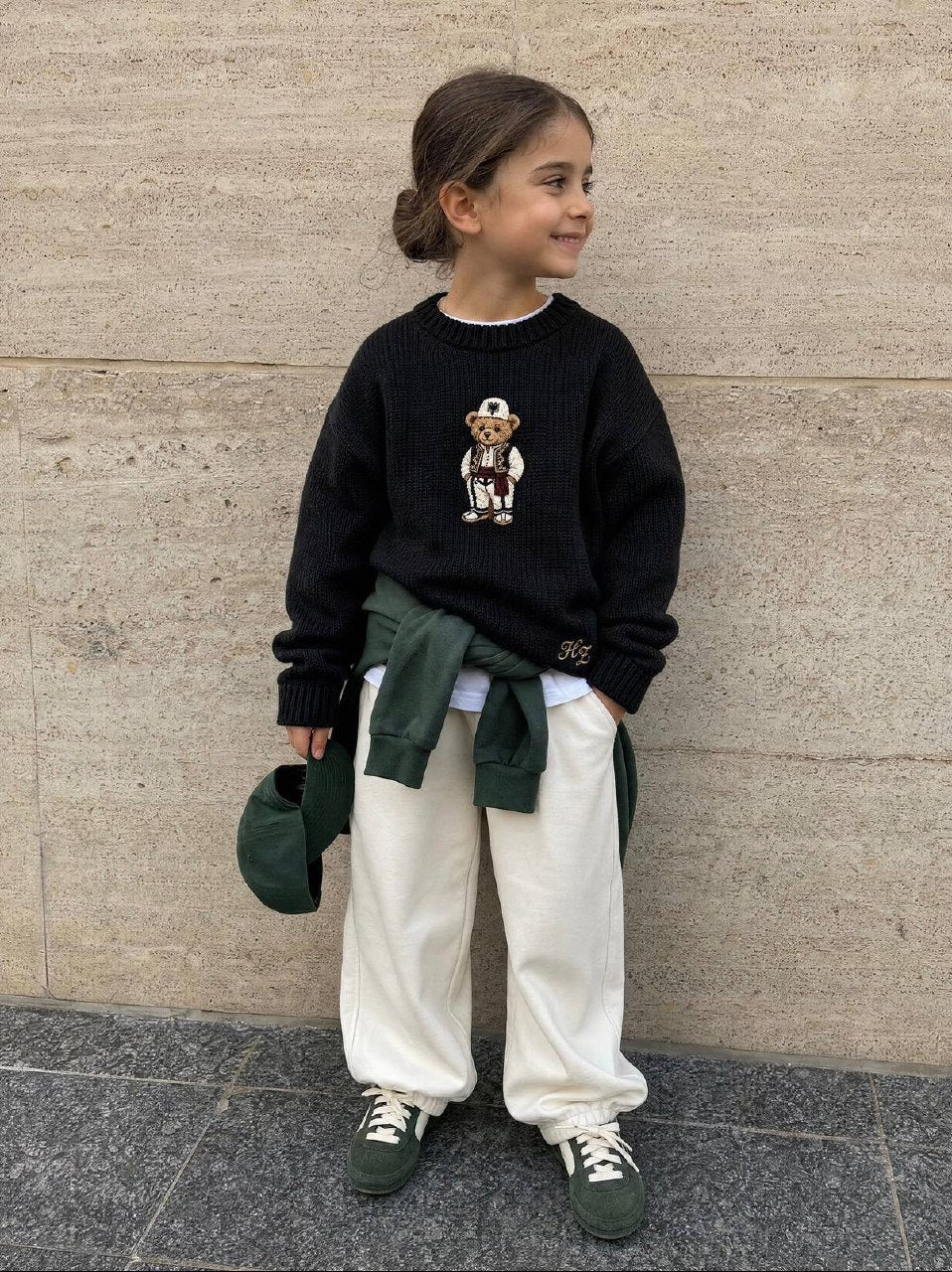 Albanian Ted Dua Bear Sweater Set for kids (Black + Burgundy), the black sweater on a girl smiling by a travertine wall