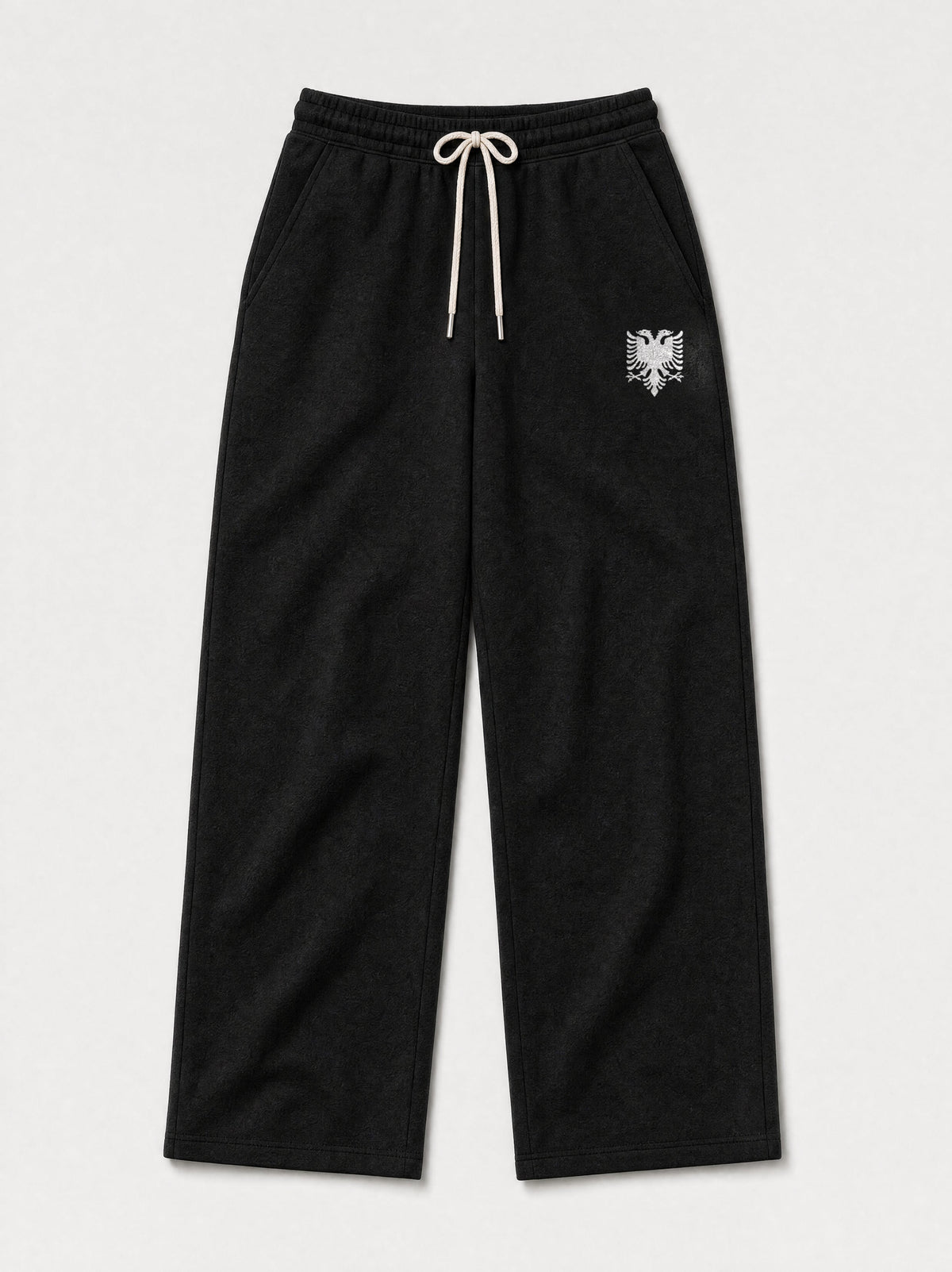 Design preview: Hajde Zemer HZ Essential Eagle Sweatpants in black, front flat lay with the cream double-headed eagle at one hip