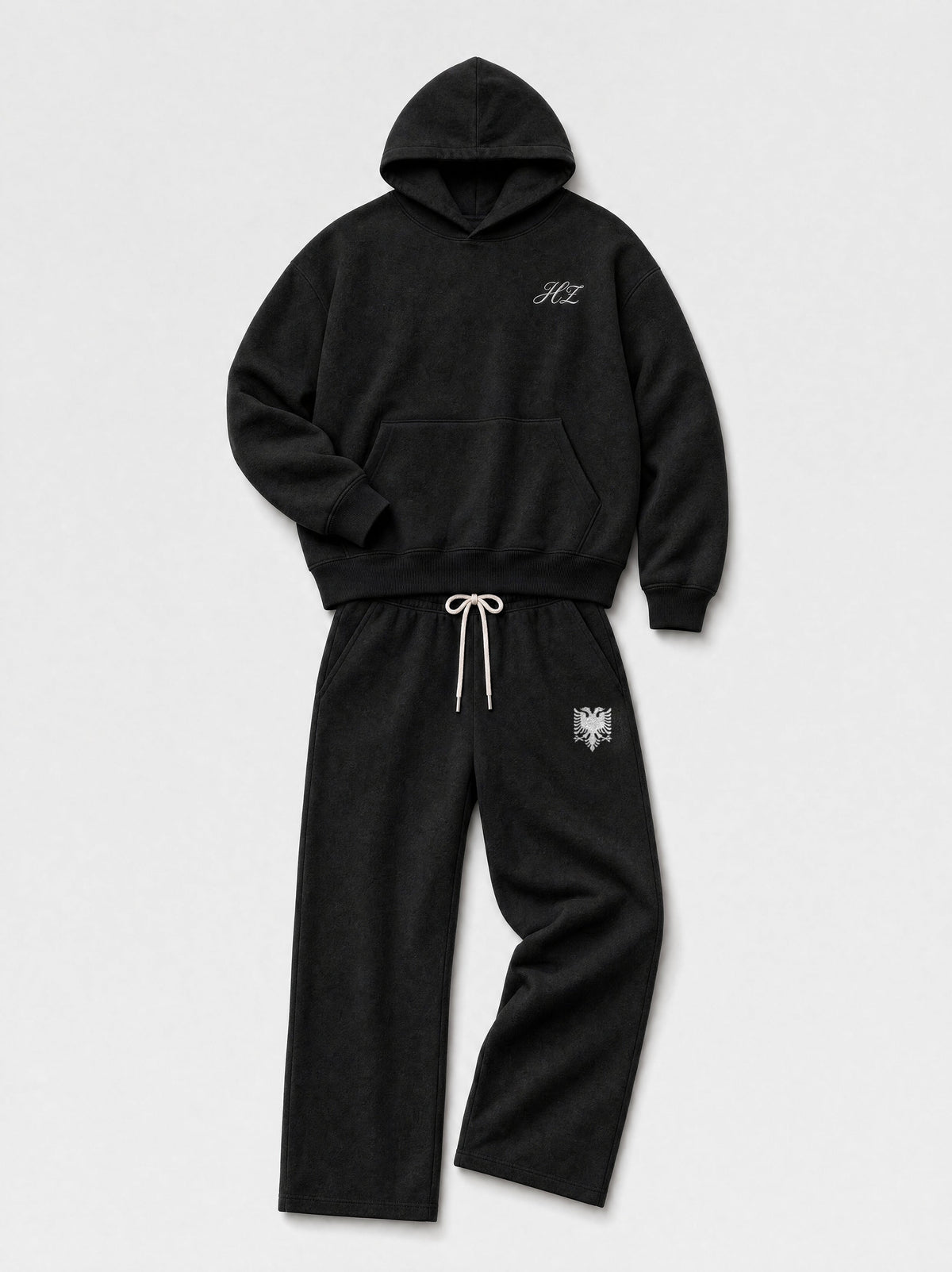 Design preview: Hajde Zemer HZ Essential Eagle Set in black, folded flat lay with the cream eagle at the sweatpant hip