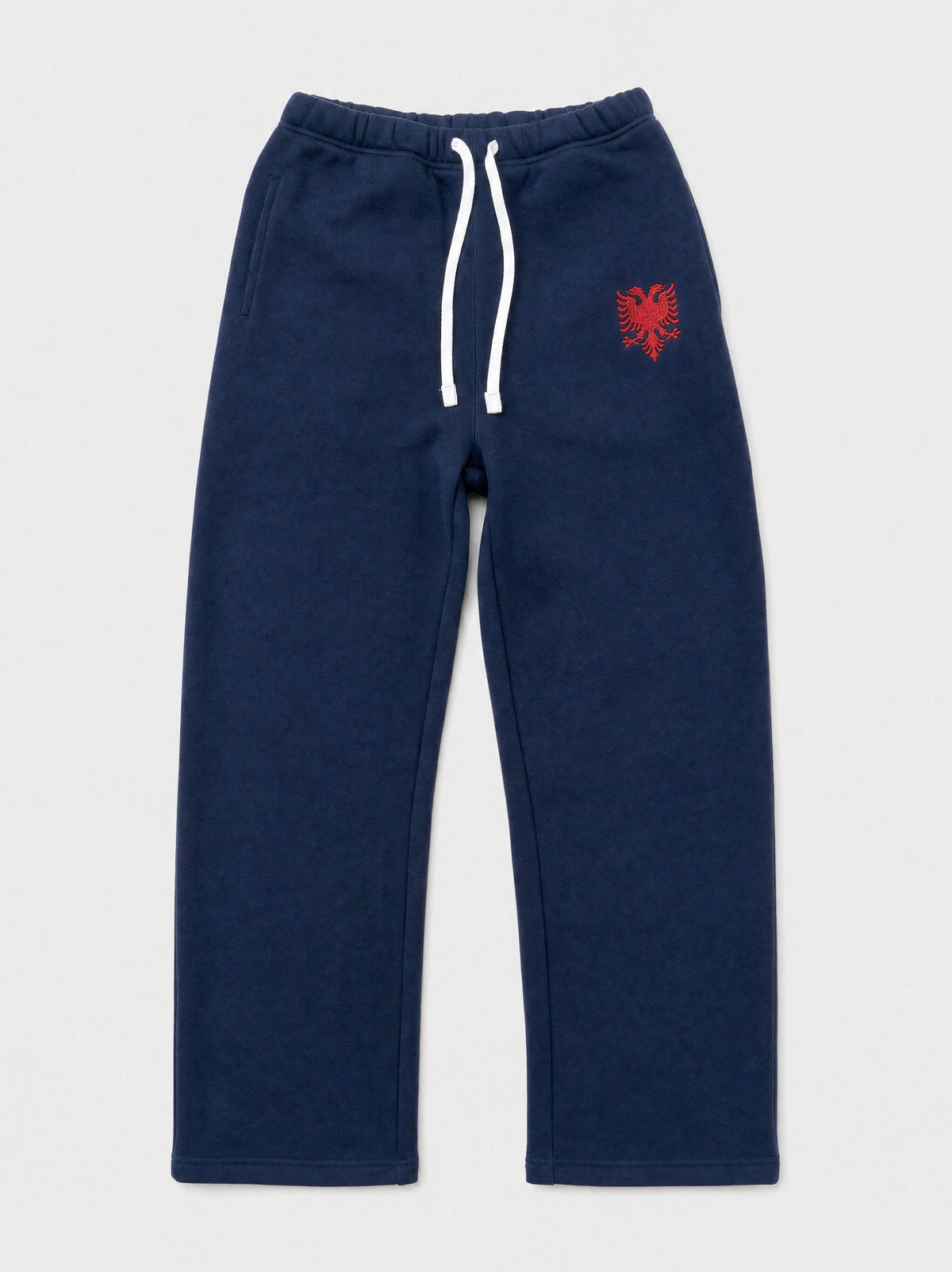 Design preview: Hajde Zemer HZ Essential Eagle Sweatpants in blue navy, front flat lay with the white drawcord and the red double-headed eagle on the thigh