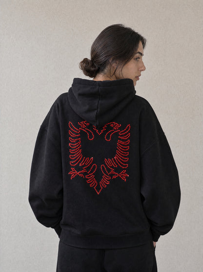 Woman wearing the black Hajde Zemer Essential Eagle hoodie, back view, red outline Albanian eagle across the back