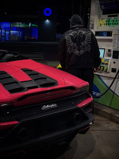 Albanian Black Eagle Jacket worn at gas station with red Lamborghini — eagle outline embroidery nighttime lifestyle shot | Hajde Zemer