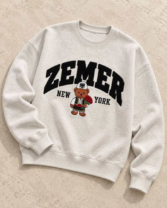 ZEMER Bear Crewneck flat lay on stone, angled, showing ribbed collar cuffs and hem