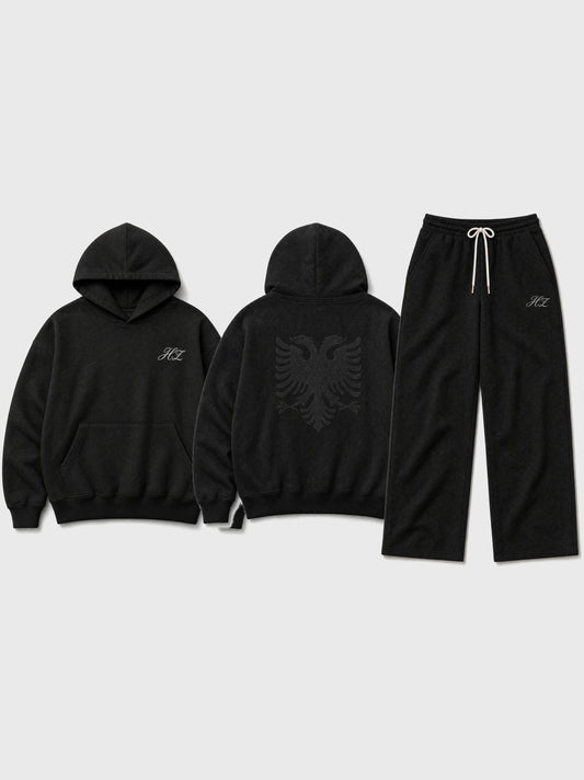 Hajde Zemer Essential Eagle blackout set flat lay: hoodie front with HZ script, hoodie back with tonal Albanian eagle print, and matching sweatpants in black.