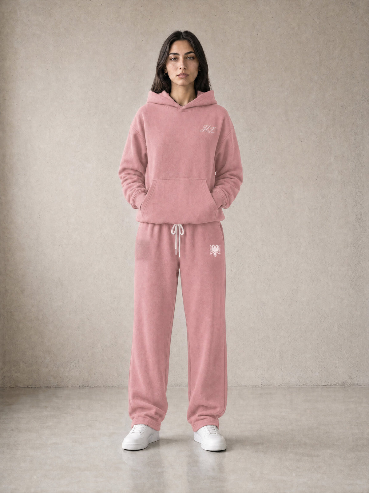 Design preview: Hajde Zemer HZ Essential Eagle Set in dusty rose pink, front view on a female model - cream HZ script on the chest, cream double-headed eagle at the sweatpant hip