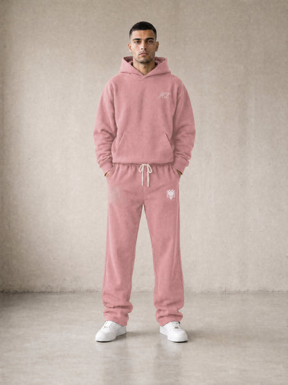 Design preview: Hajde Zemer HZ Essential Eagle Set in dusty rose pink, front view on a male model - cream HZ script on the chest, cream double-headed eagle at the sweatpant hip
